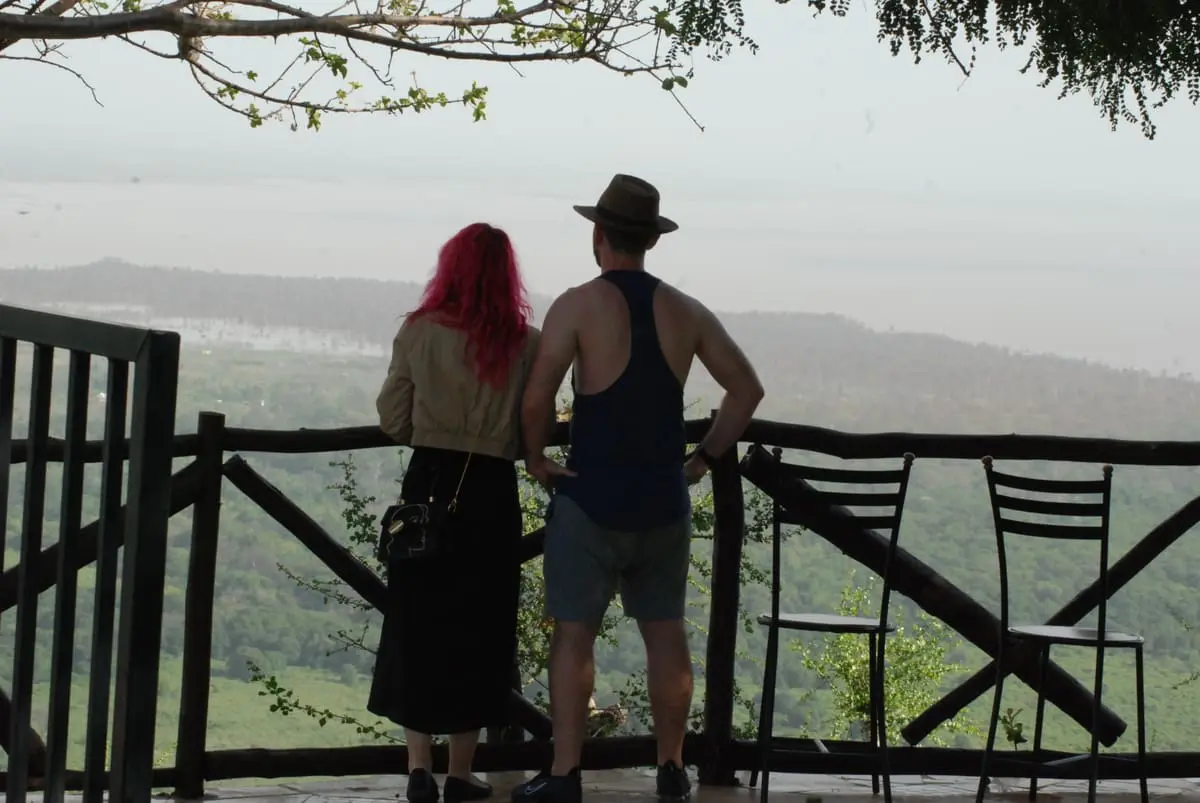 Couple on a lodge deck looking out over forested hills