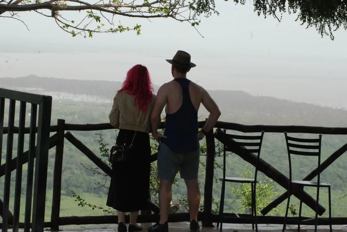 Couple looking out from a lodge deck over a green valley