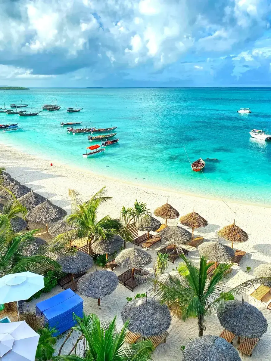 Dhows on turquoise water off a white sand beach in Zanzibar